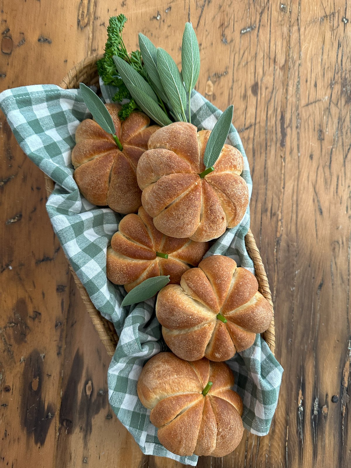 Pumpkin shaped dinner rolls in a wicker basket.