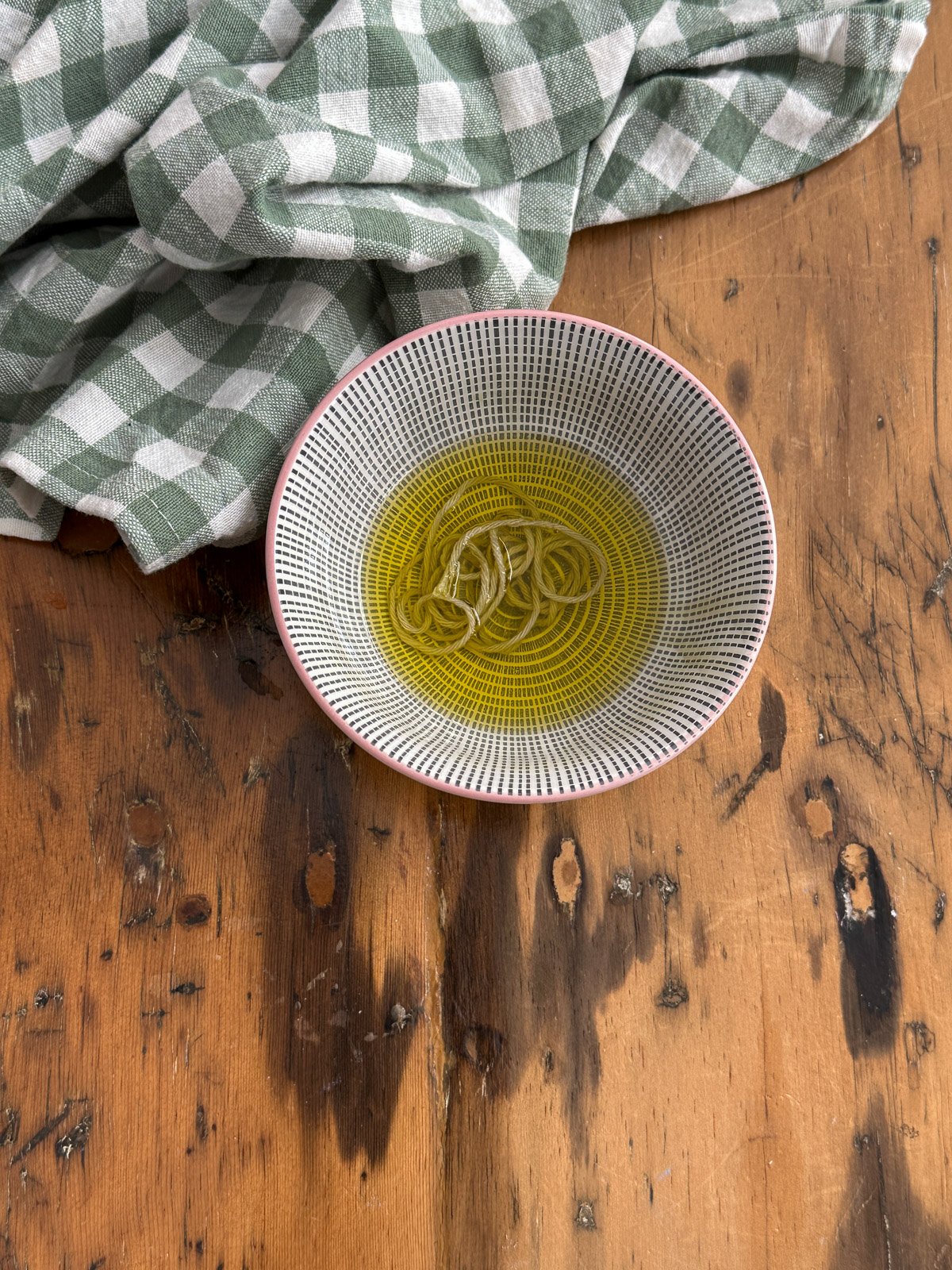 Kitchen string cut into pieces and soaking in a bowl of olive oil, ready to use to tie pumpkin dinner rolls into shape.