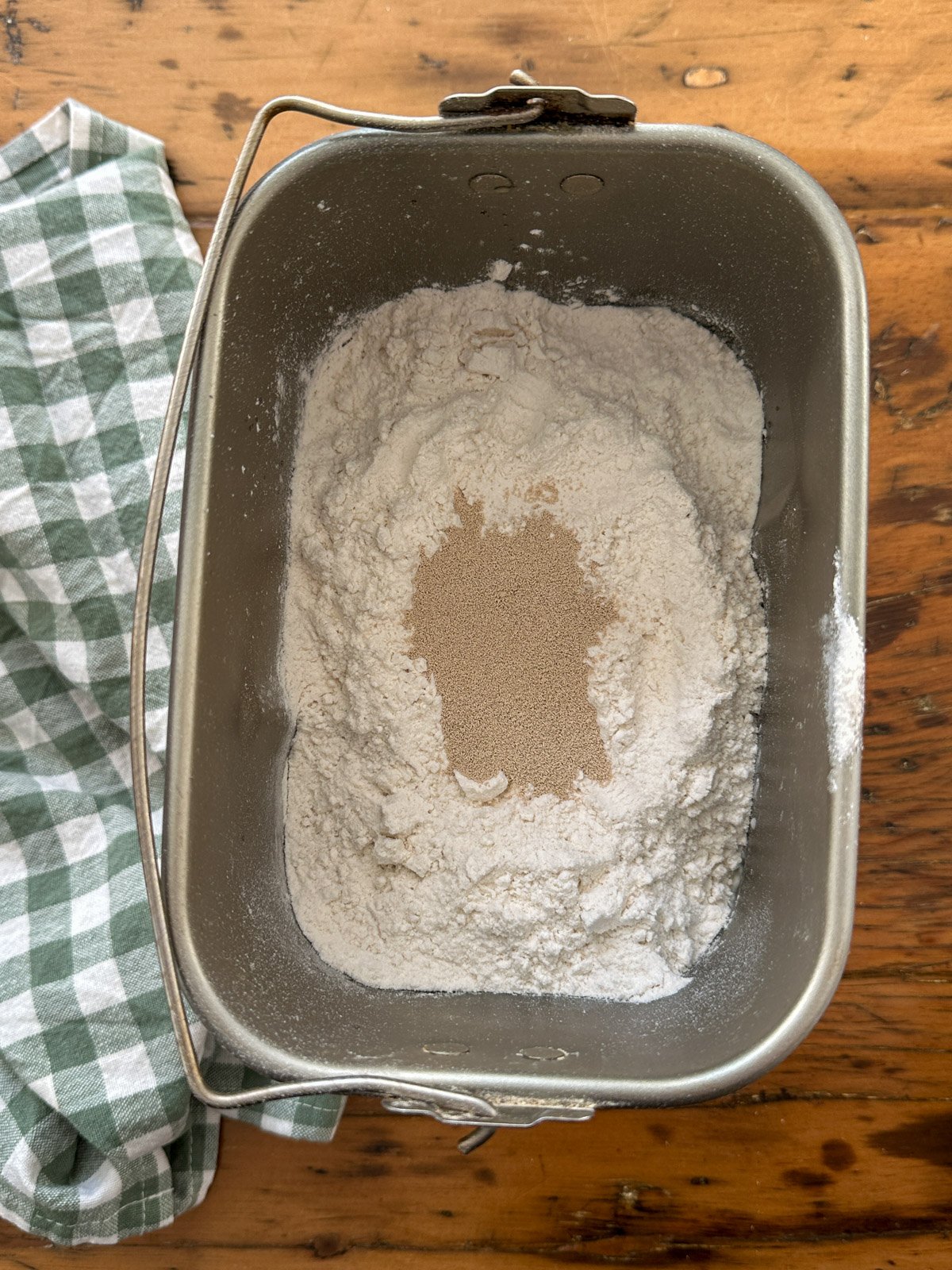 Pumpin shaped dinner roll ingredients layered in bread making machine tray.
