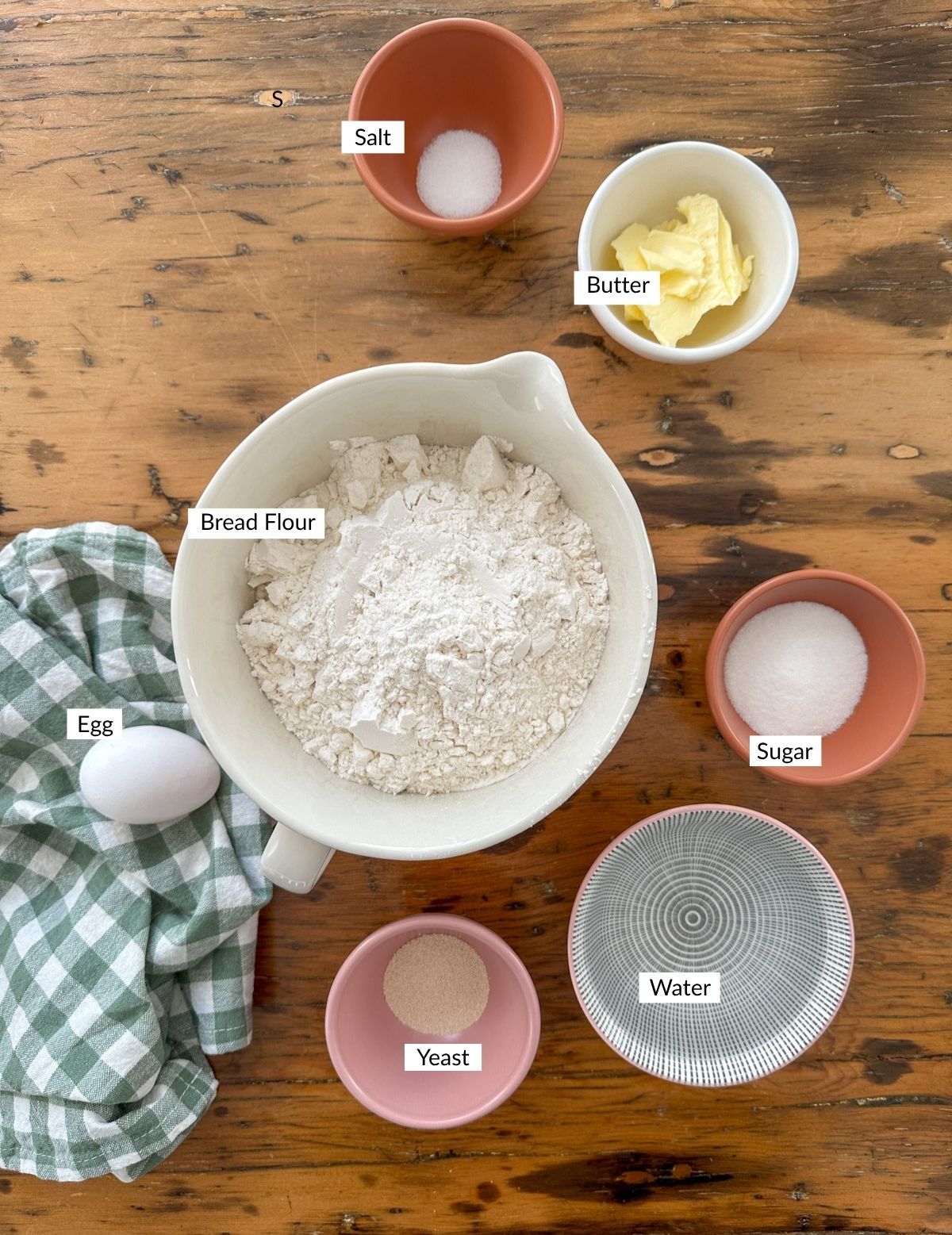 Pumpkin shaped dinner roll ingredients in bowls on a table.