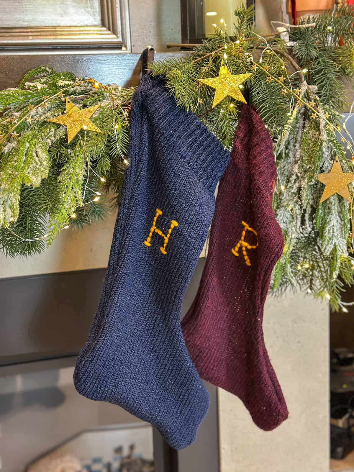DIY Harry Potter Christmas stockings with stitched initials hanging on mantel for homemade holiday decorations.