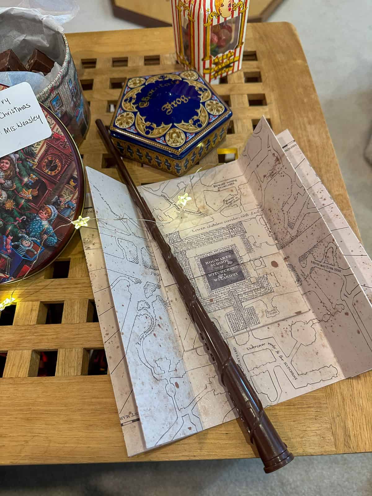 Marauder's Map with wand and chocolate frogs on coffee table for Harry Potter Christmas decorations and themed decor.