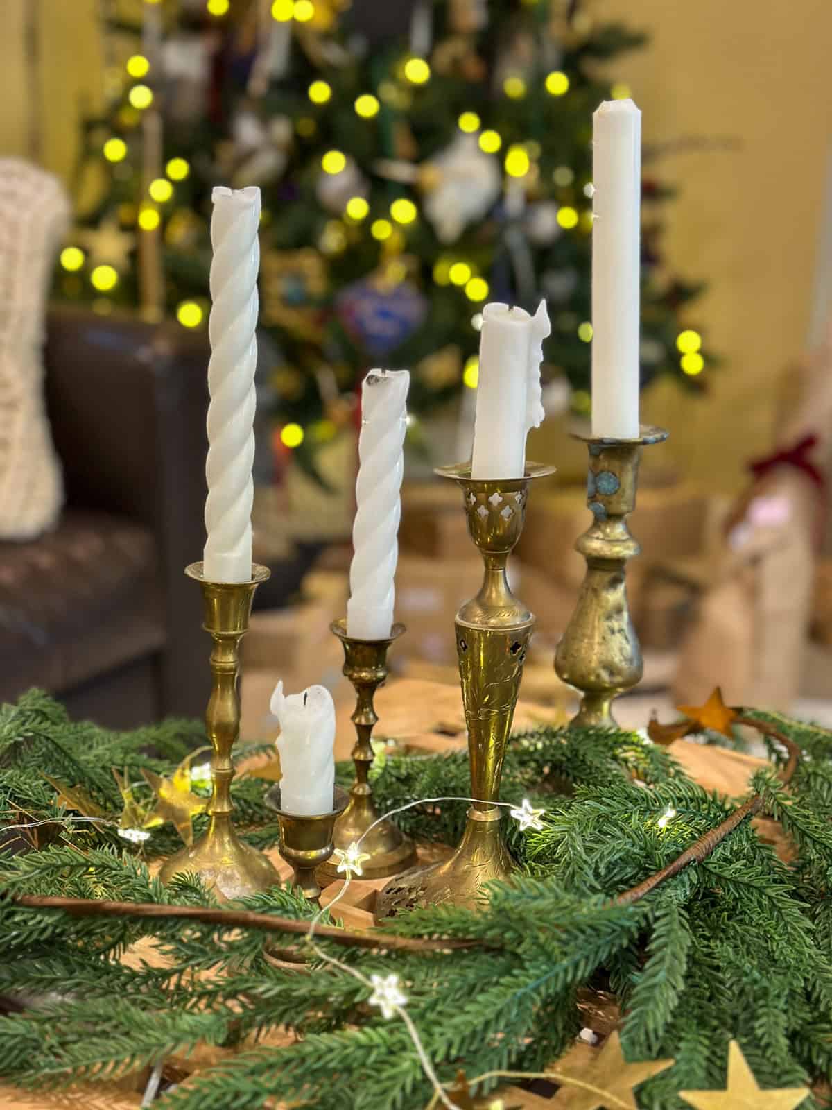Vintage brass candlesticks with white candles and greenery on  a Harry Potter Christmas coffee table for themed holiday decor.