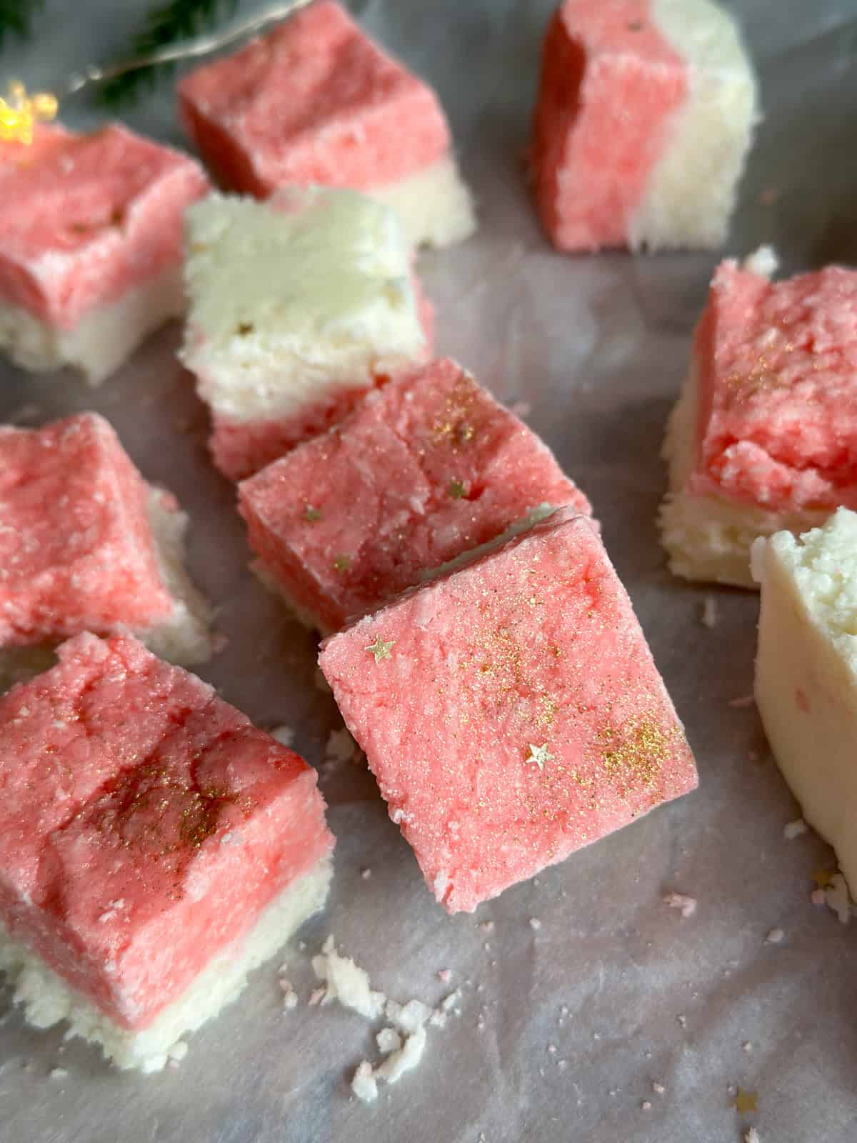 Pink and white coconut ice, cut into squares and decorated with star sprinkles.