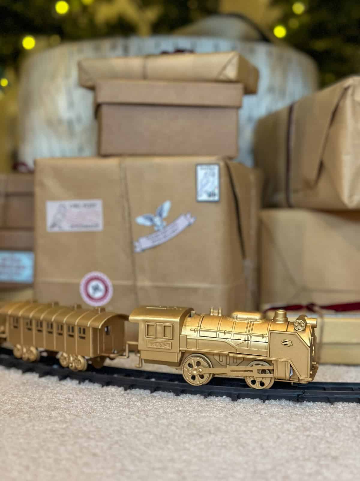 Gold Hogwarts Express train circling base of Harry Potter Christmas tree with owl post packages for DIY decorations.