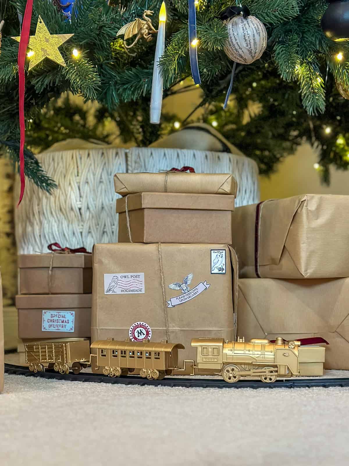 Gold Hogwarts Express train with owl post packages under Harry Potter Christmas tree for DIY holiday decorations.