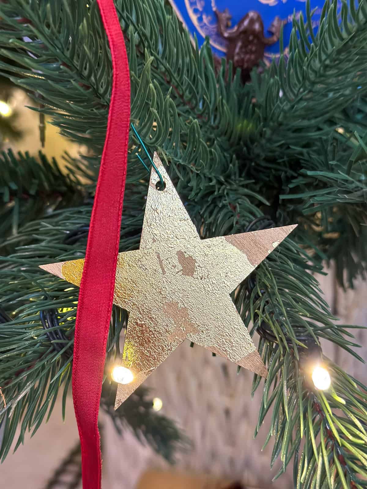 DIY gold star ornament with gold leaf detail  on a Harry Potter themed Christmas tree with twinkling lights.