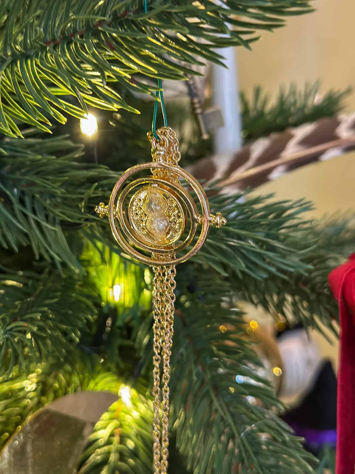 Time turner ornament with gold chain on Harry Potter Christmas tree for DIY holiday decorations.