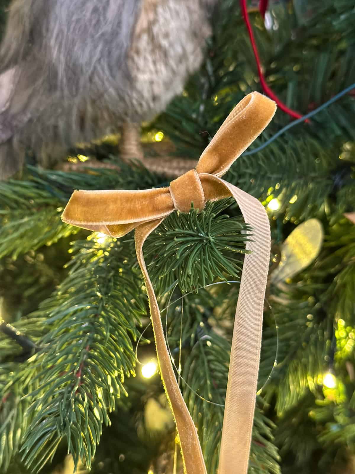 Gold velvet Hufflepuff house ribbon bow on Harry Potter Christmas tree with lights.