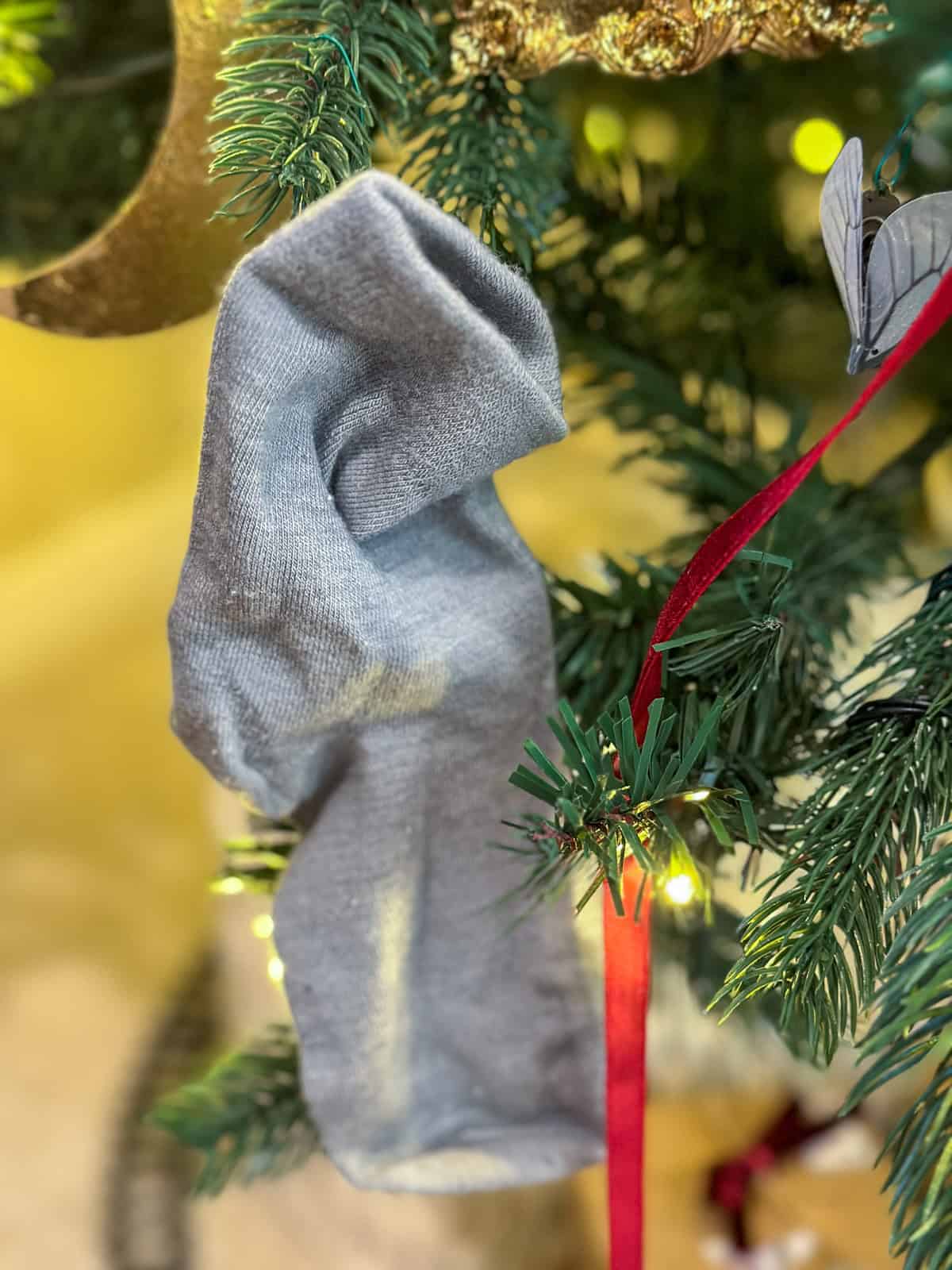 Dobby's sock ornament with red ribbon on Harry Potter Christmas tree for DIY holiday decorations.