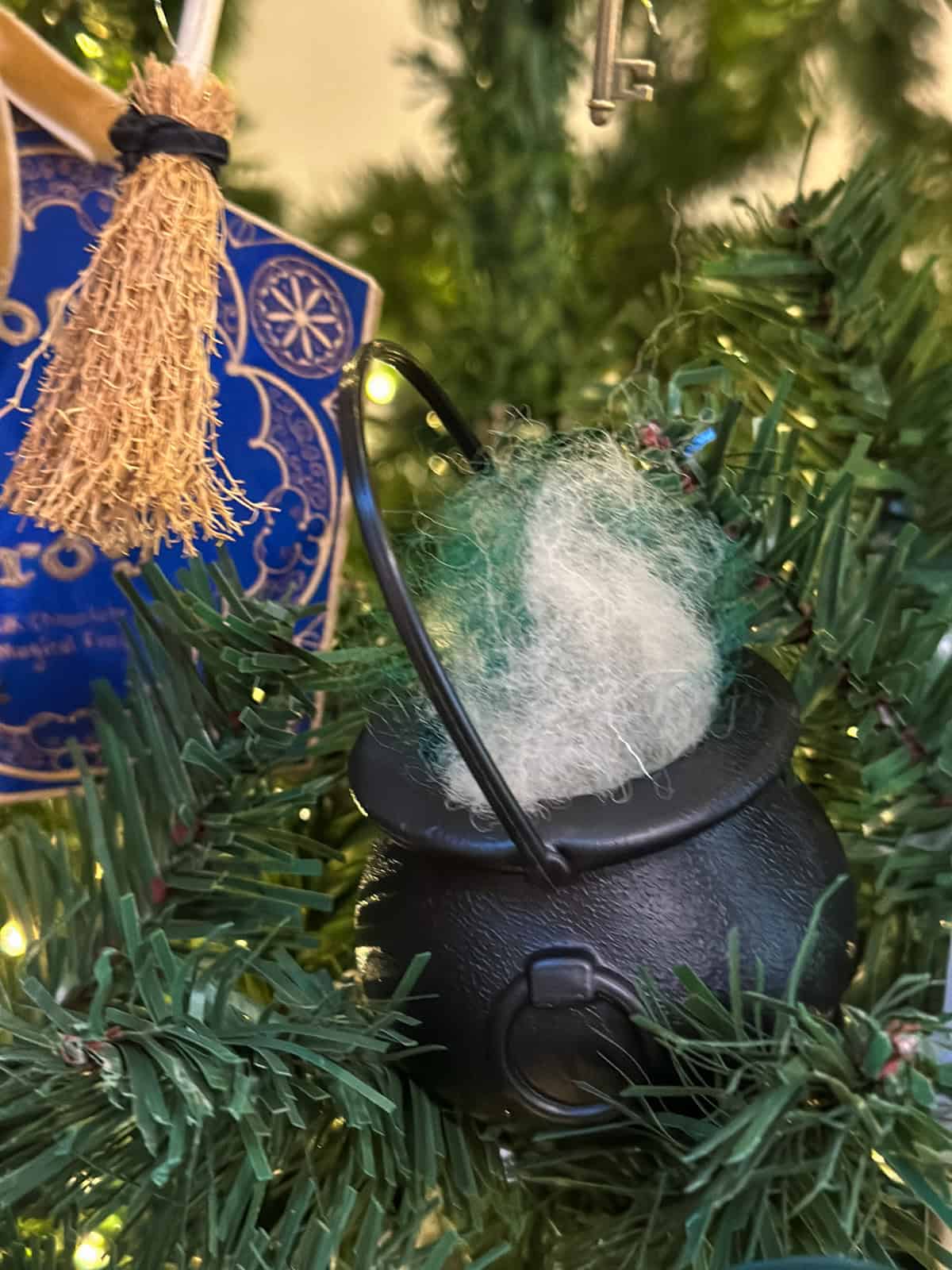Mini black cauldron ornament filled with white wool potion on Harry Potter Christmas tree for DIY holiday decorations.