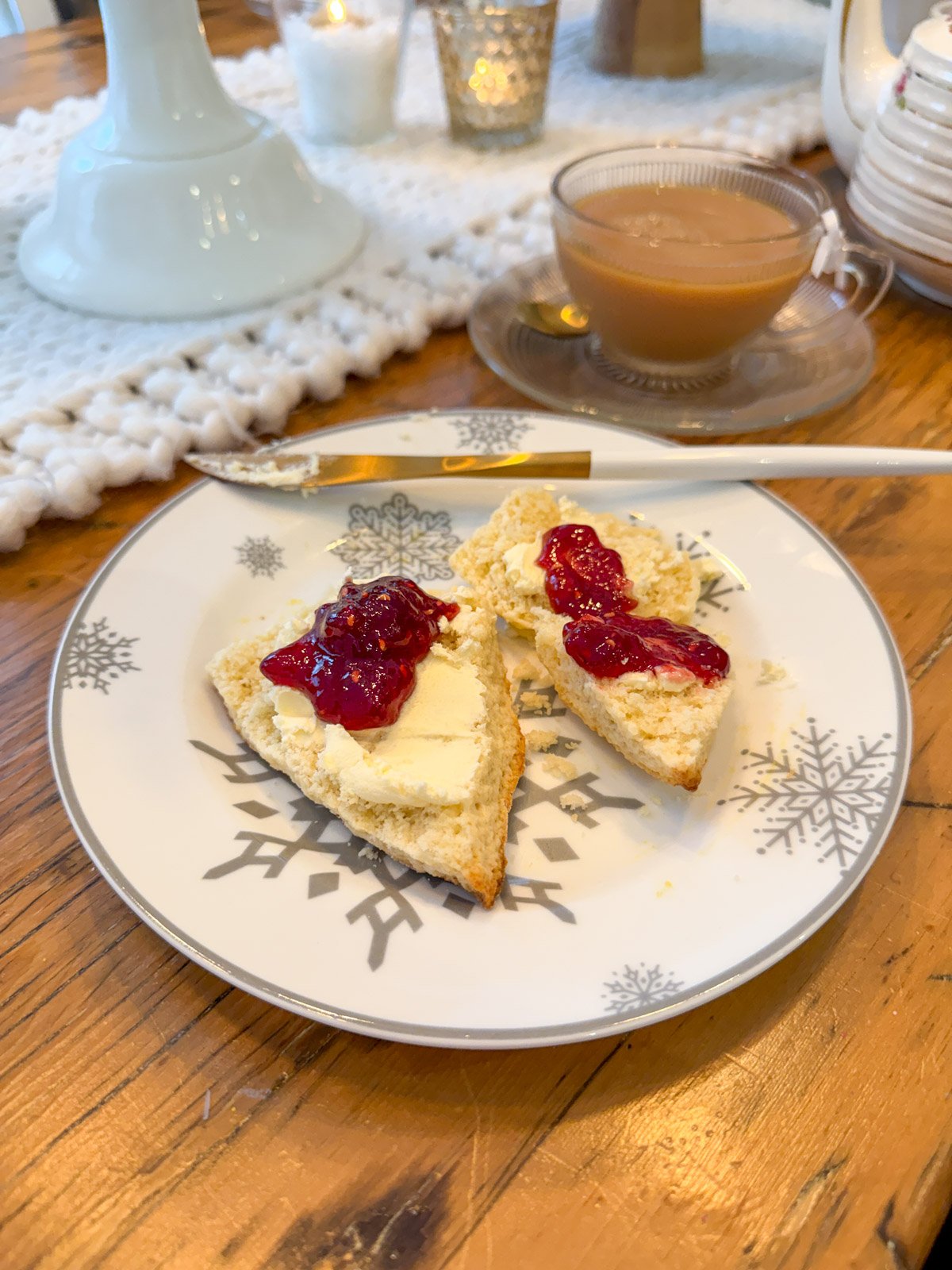 Plate with a scone covered in clotted cream and jam at a winter-themed tea party.