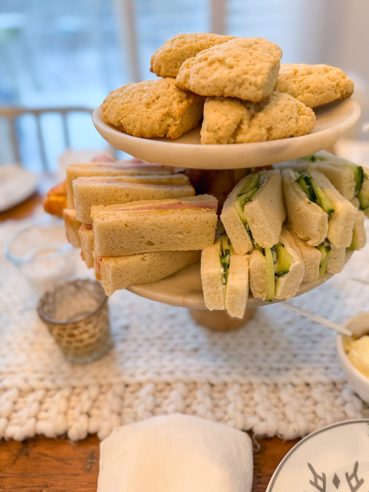Tiered tray of tea sandwiches and scones for a winter tea party.