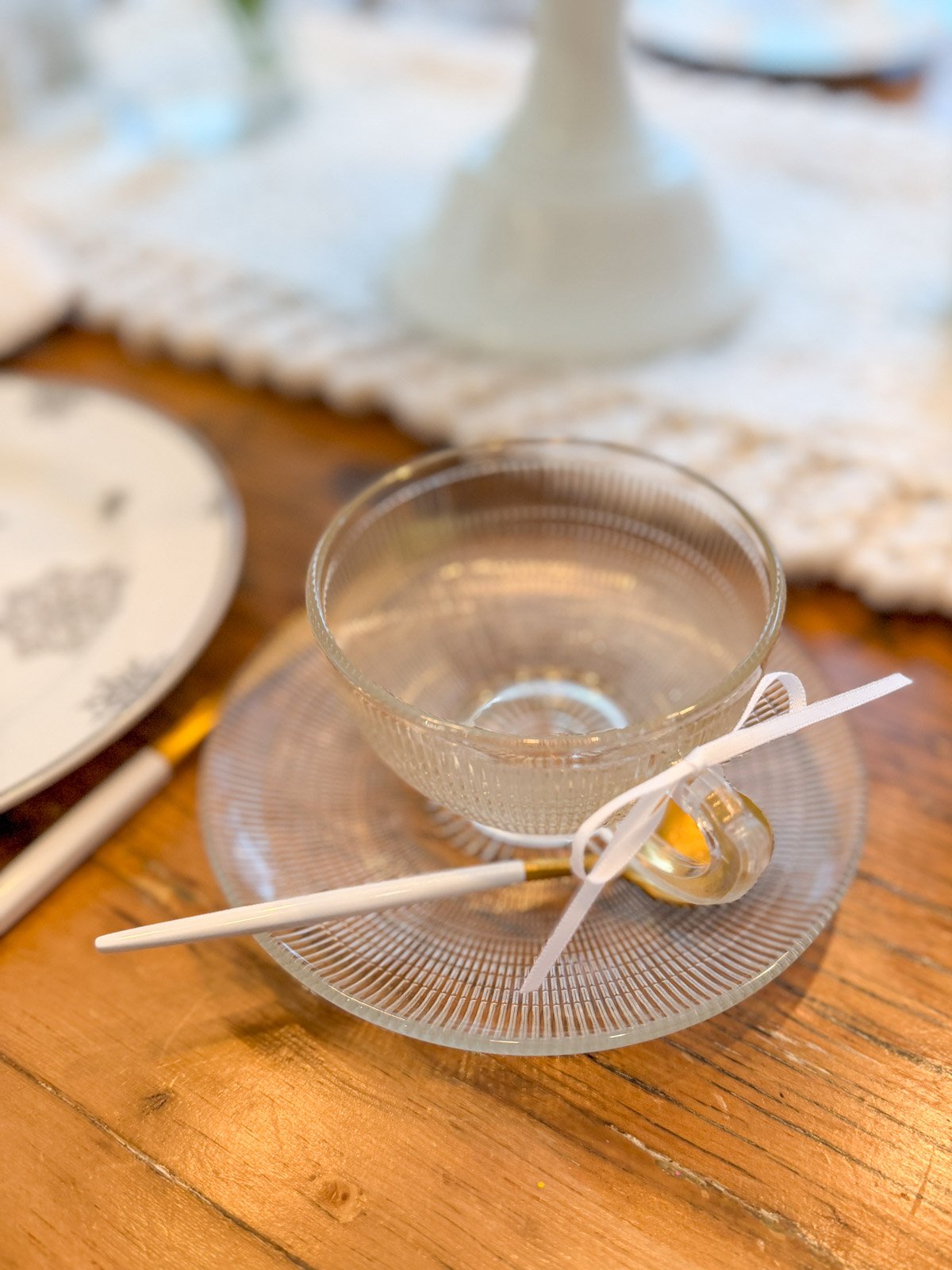 Vintage glass tea cup with white ribbon bow for a winter tea party.