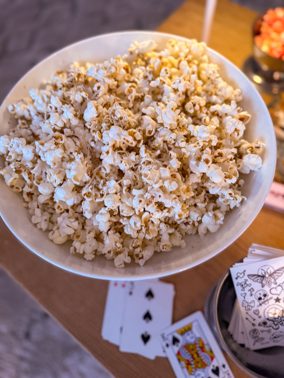 Circus party sideshow coffee table styled with a bowl of truffle popcorn, and scattered playing cards.