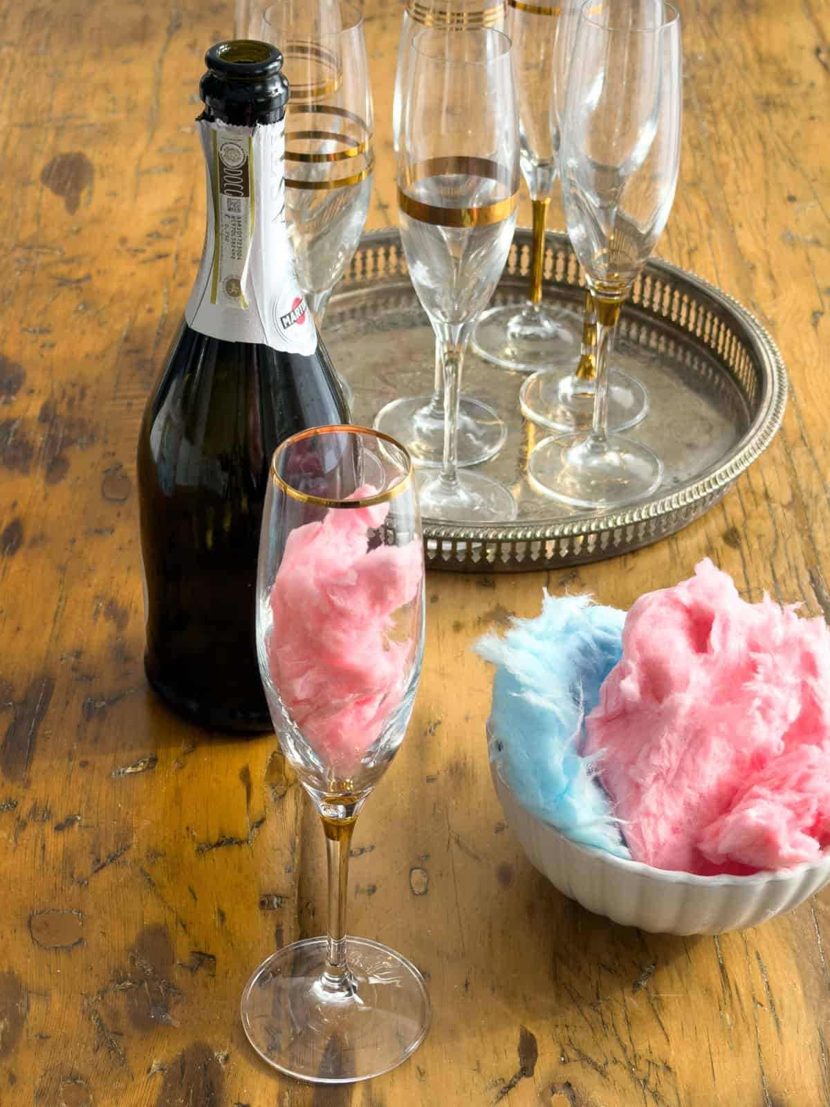 Pink cotton candy placed inside champagne flute for cotton candy cocktail step one.