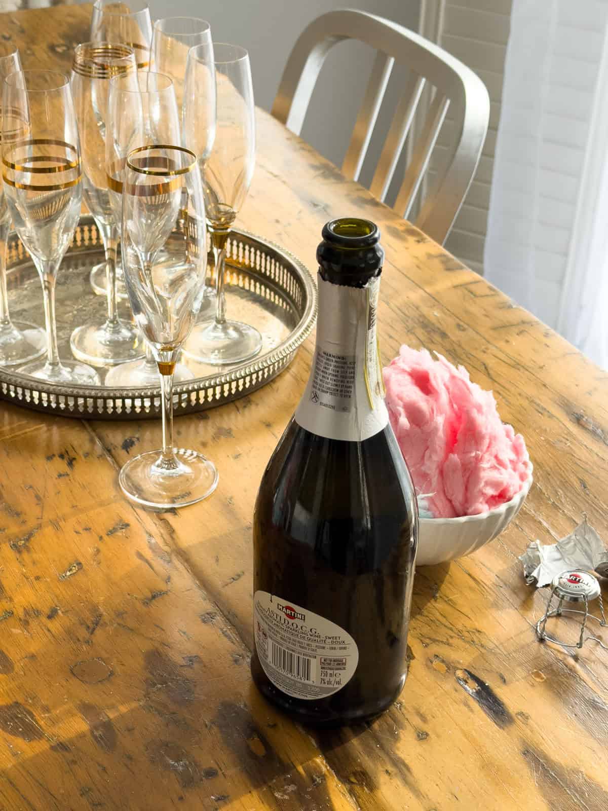 Self-serve cotton candy cocktail party station with champagne flutes on silver tray and bowl of pink cotton candy.
