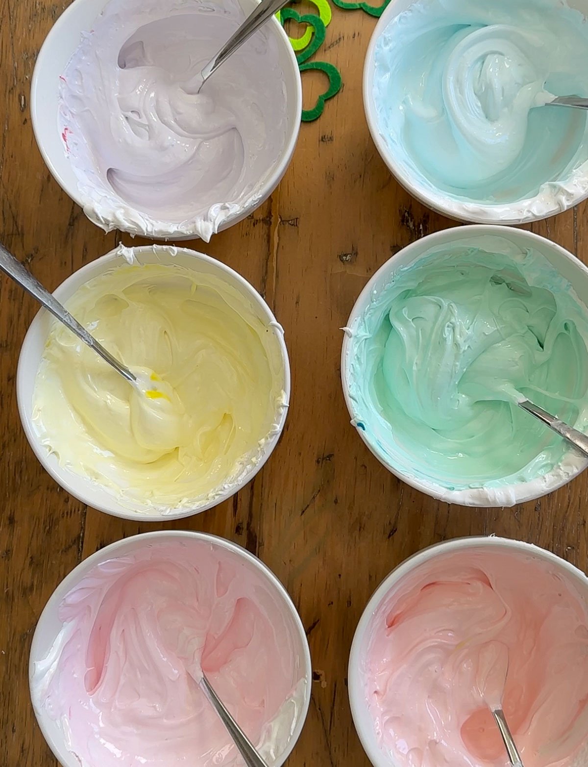 Six bowls of marshmallow mixture colored in rainbow colors red, orange, yellow, green, blue,and purple.