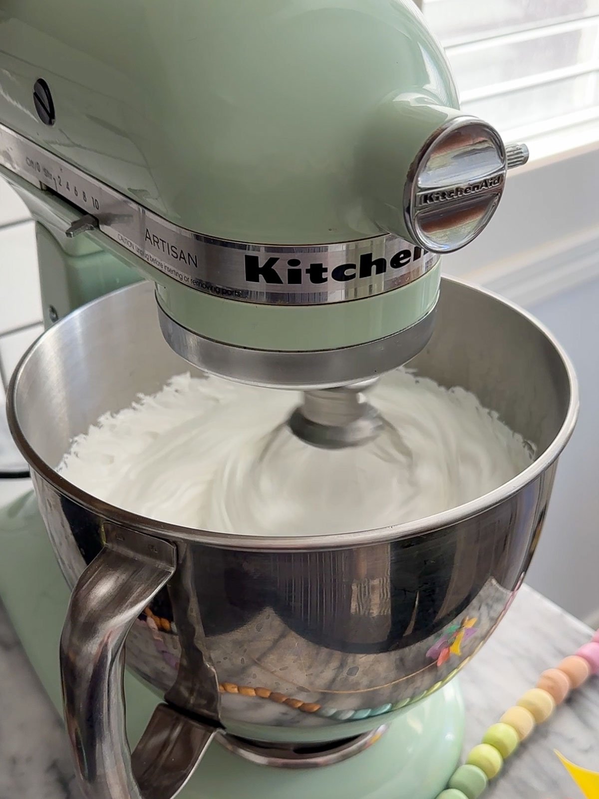 White fluffy marshmallow mixture being whipped in stand mixer.