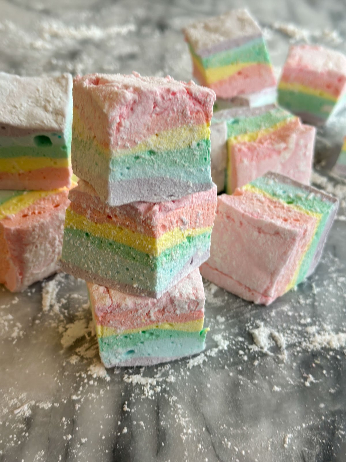 Beautiful rainbow marshmallows stacked ontop of each other,  showing all six rainbow color layers.