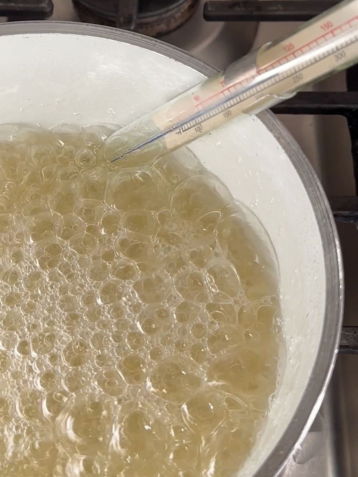 Candy thermometer measuring sugar syrup at 240 degrees for strawberry marshmallow recipe.