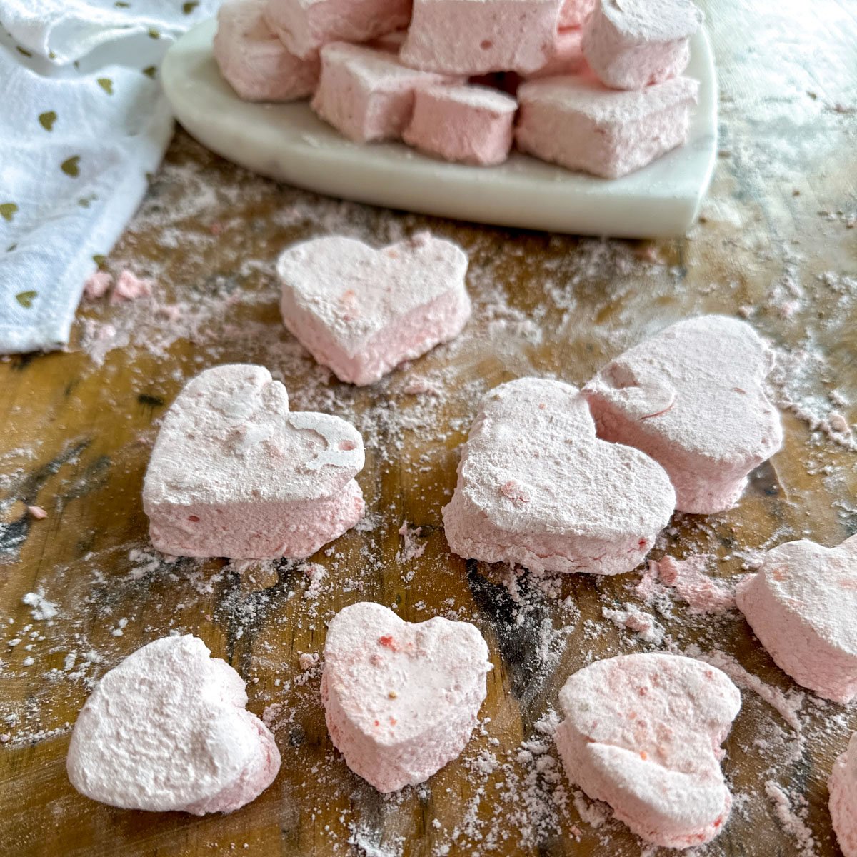 Close up of pink heart-shaped strawberry marshmallows dusted with coating.