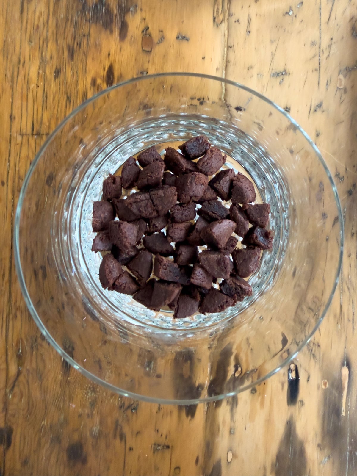 Two-bite brownies quartered and layered across the bottom of a large glass trifle bowl.