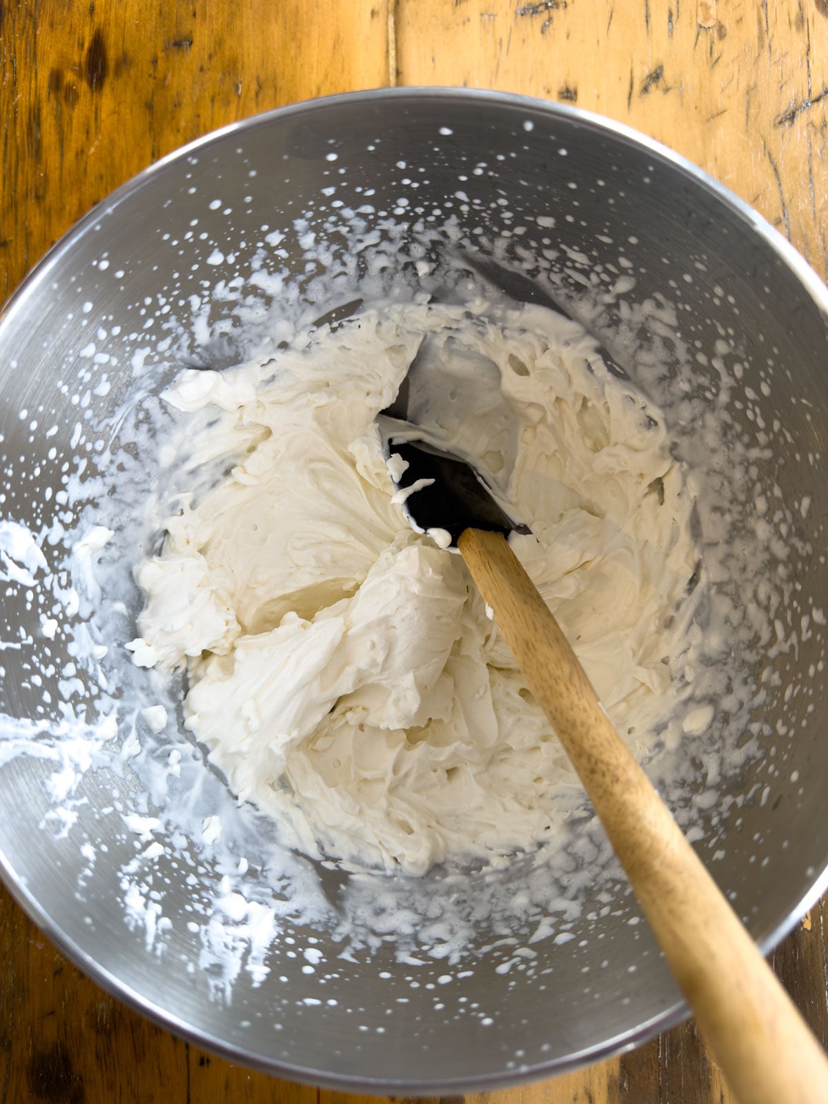 Freshly whipped cream in a metal mixing bowl ready to be layered in an Easter trifle.