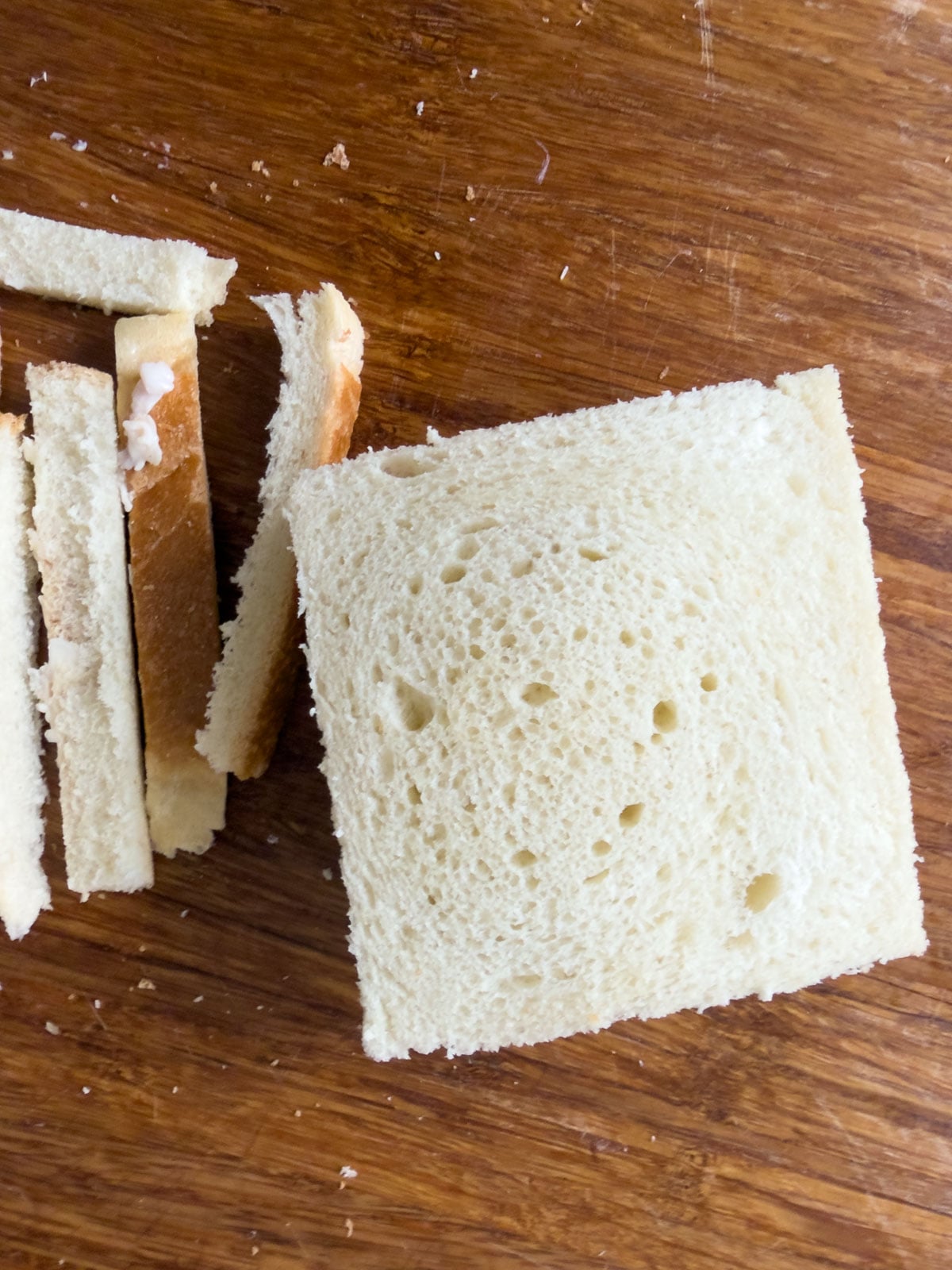 Chicken salad finger sandwiches on a cutting board with crusts trimmed and cut into rectangles.