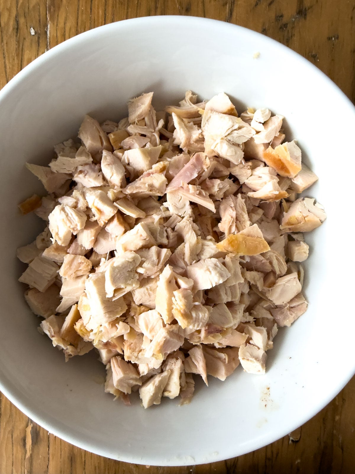 Diced rotisserie chicken in a white bowl ready to be made into chicken salad finger sandwiches.