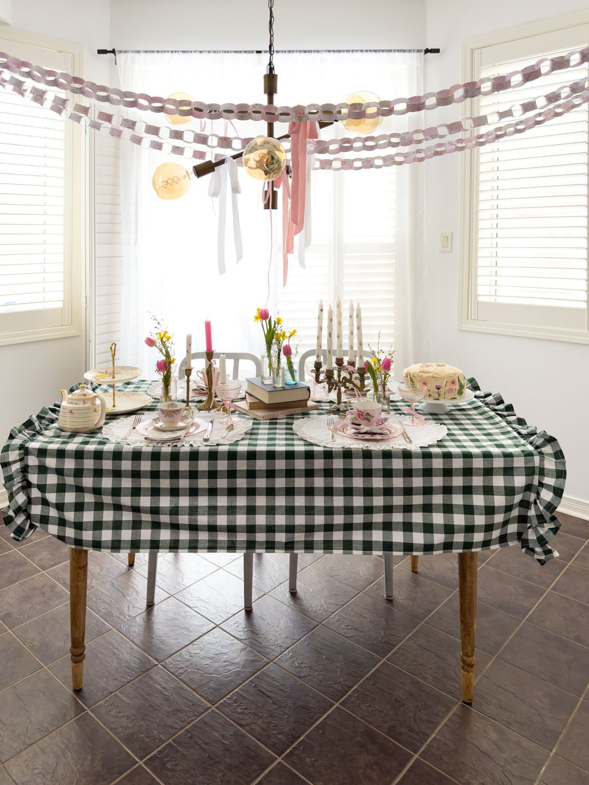 Green gingham tablecloth with vintage teacups, candelabra, tulips and daffodils set for a Little Women party.
