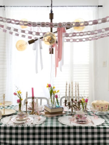 Green gingham tablecloth with vintage teacups, candelabra, tulips and daffodils set for a Little Women party.