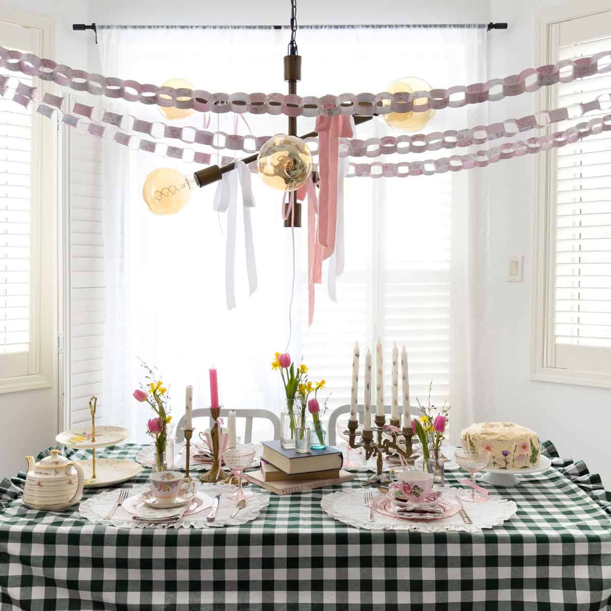 Green gingham tablecloth with vintage teacups, candelabra, tulips and daffodils set for a Little Women party.