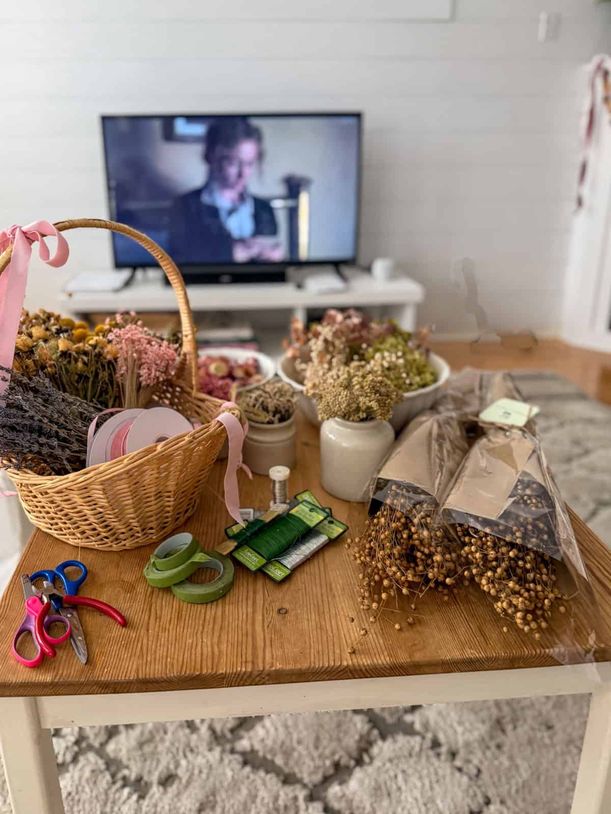 Flower crown supplies laid out at a Little Women party with the 2019 Little Women film playing on the TV in the background