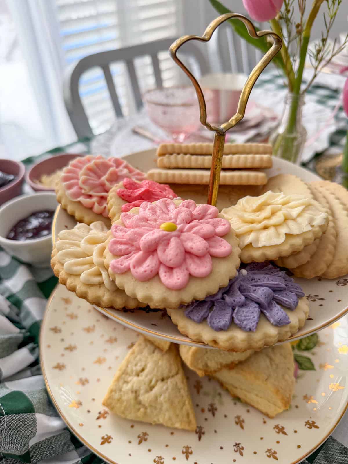 Two-tiered stand with flower-shaped frosted sugar cookies and scones at a Little Women vintage tea party.