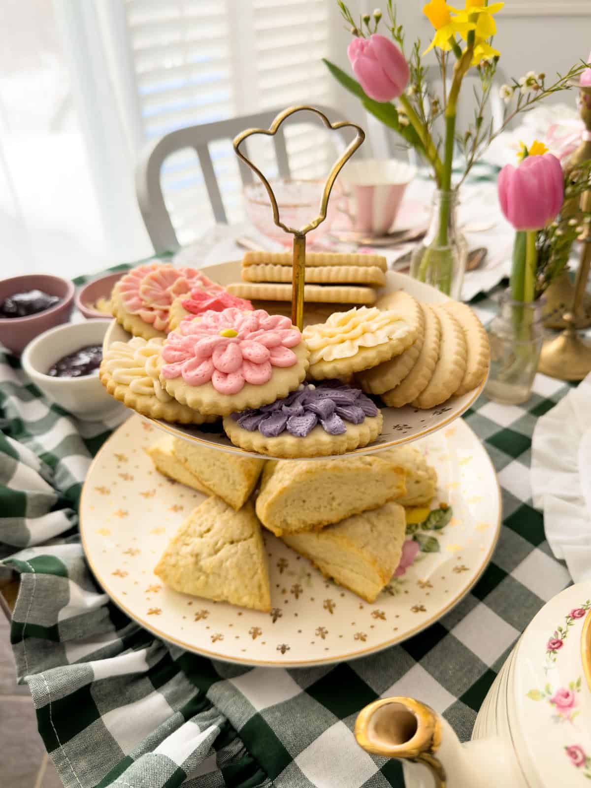 Two-tiered stand with scones and flower-shaped sugar cookies beside a vintage teapot at a Little Women tea party.