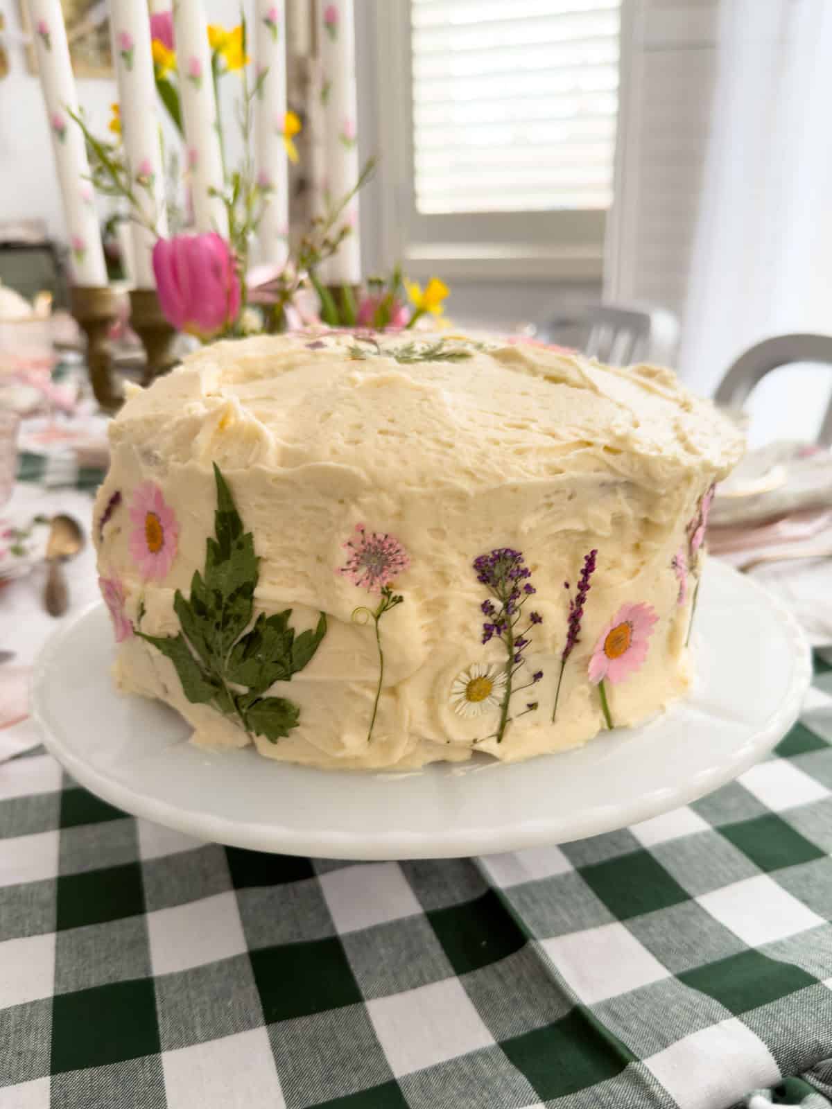 Rustic buttercream cake decorated with pressed wildflowers, daisies, lavender and fern at a Little Women vintage tea party.