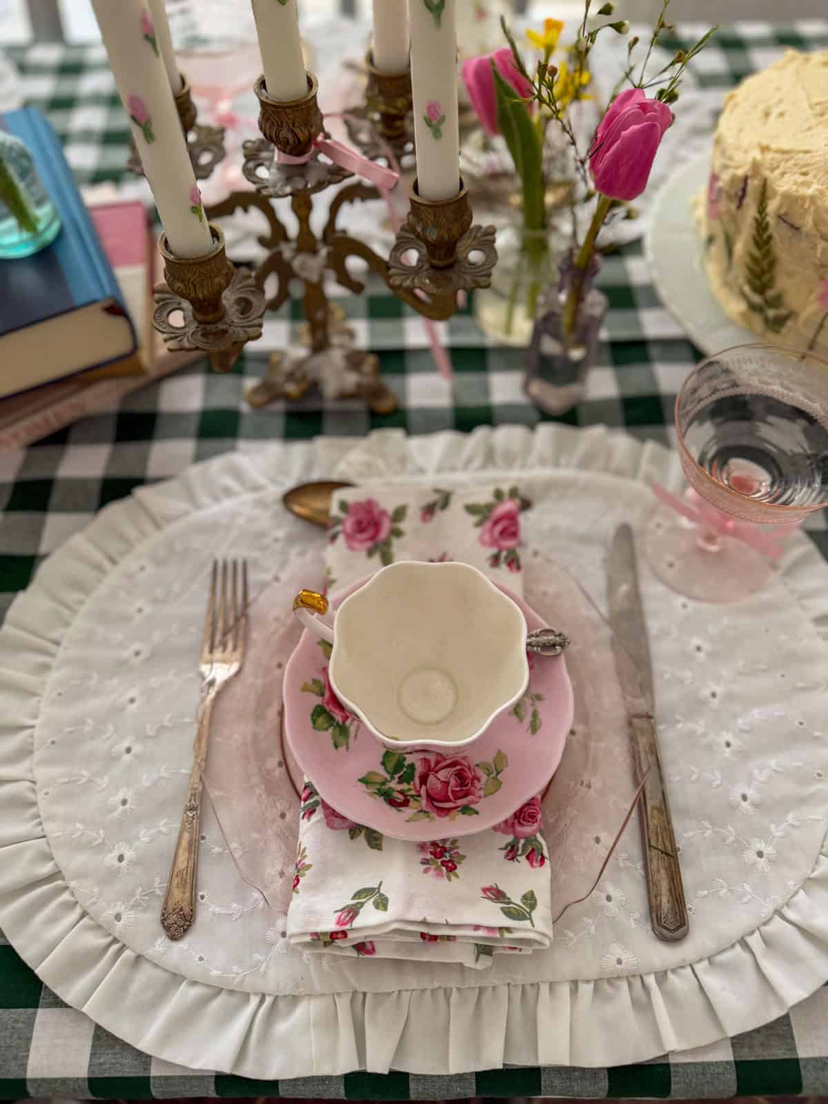 Vintage tea party place setting with mismatched floral teacup, pink depression glass coupe and silver cutlery on a Little Women party table.