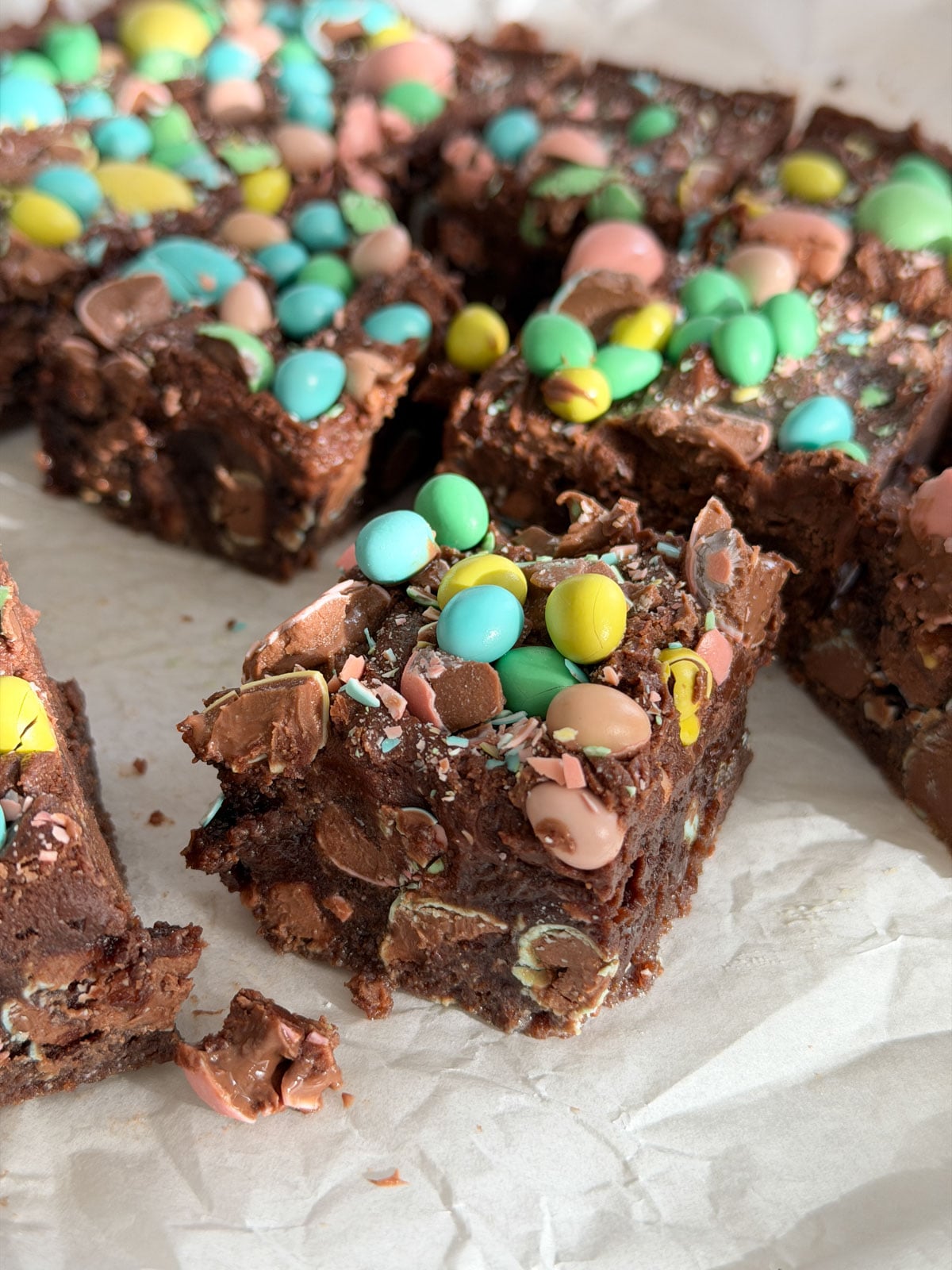 Close up of a cut mini egg brownie showing the fudgy chocolate interior studded with Cadbury mini egg pieces.