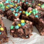 Fudgy Cadbury mini egg brownie square with pastel mini eggs on top and chocolate egg pieces visible throughout the interior.