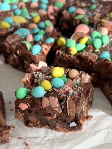 Fudgy Cadbury mini egg brownie square with pastel mini eggs on top and chocolate egg pieces visible throughout the interior.