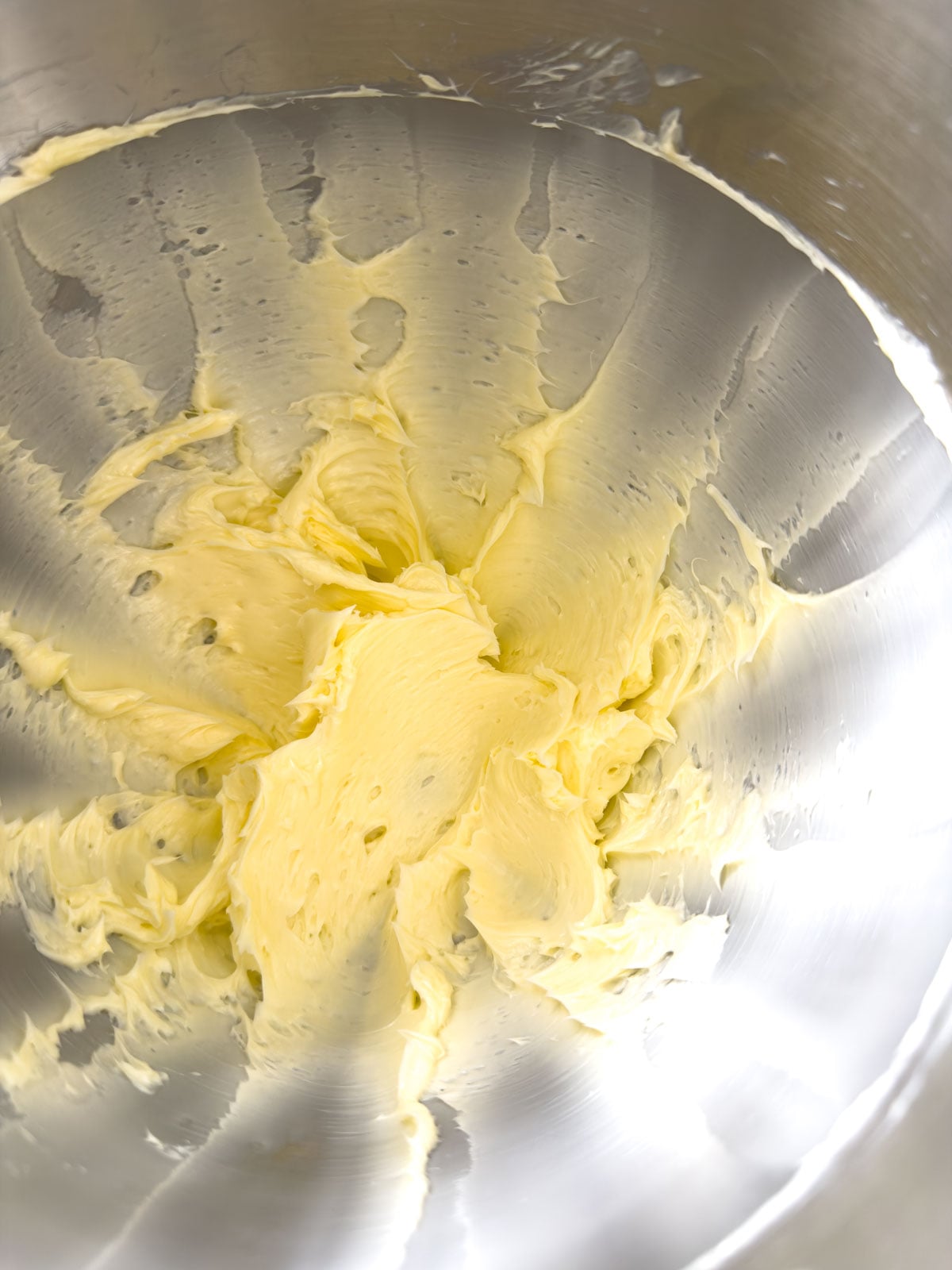 Whipped butter in a stand mixer bowl, light and fluffy, ready for herbs to be added.