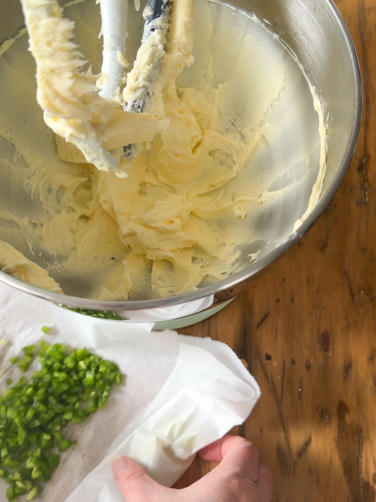 
Room temperature salted butter being added to a stand mixer bowl fitted with the paddle attachment, with finely diced jalapeno ready in the foreground.