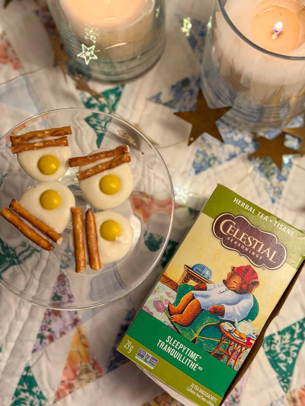 Peppermint fried egg candies made from white chocolate with yellow candy yolks and pretzel stick bacon beside a box of Sleepytime herbal tea.