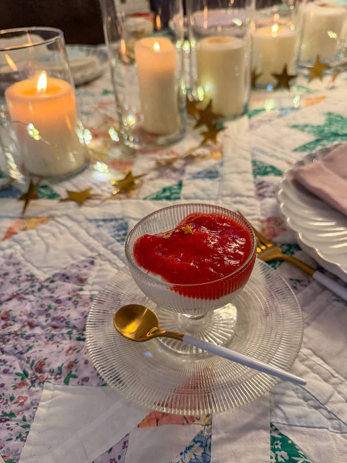 Individual yogurt and granola parfait with strawberry rhubarb compote and gold star sprinkles in a vintage ribbed coupe glass with a gold spoon.