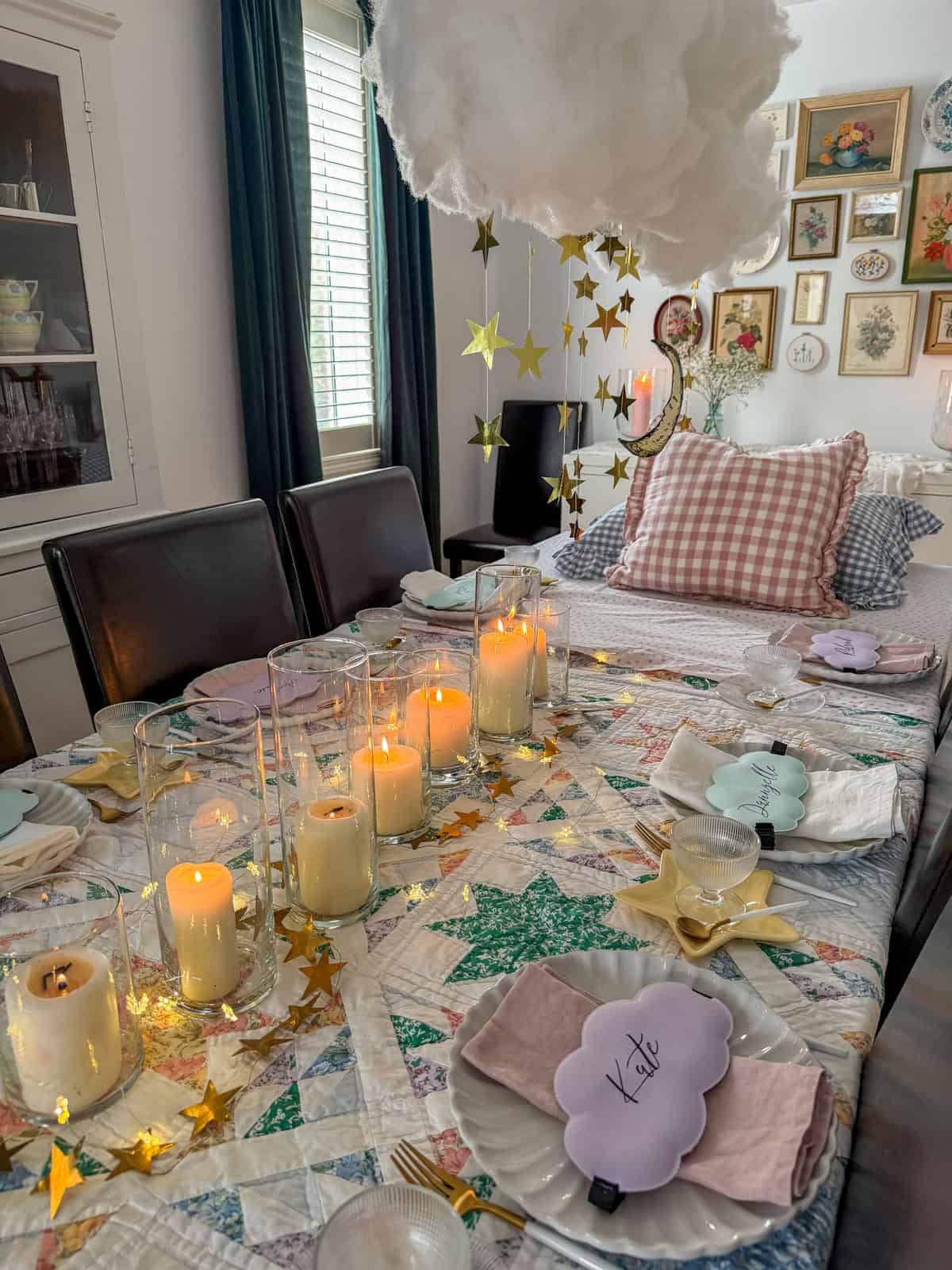 Breakfast for dinner party dining table with vintage star quilt tablecloth, pillar candles in glass cylinders, gold star confetti, and gingham pillow headboard.
