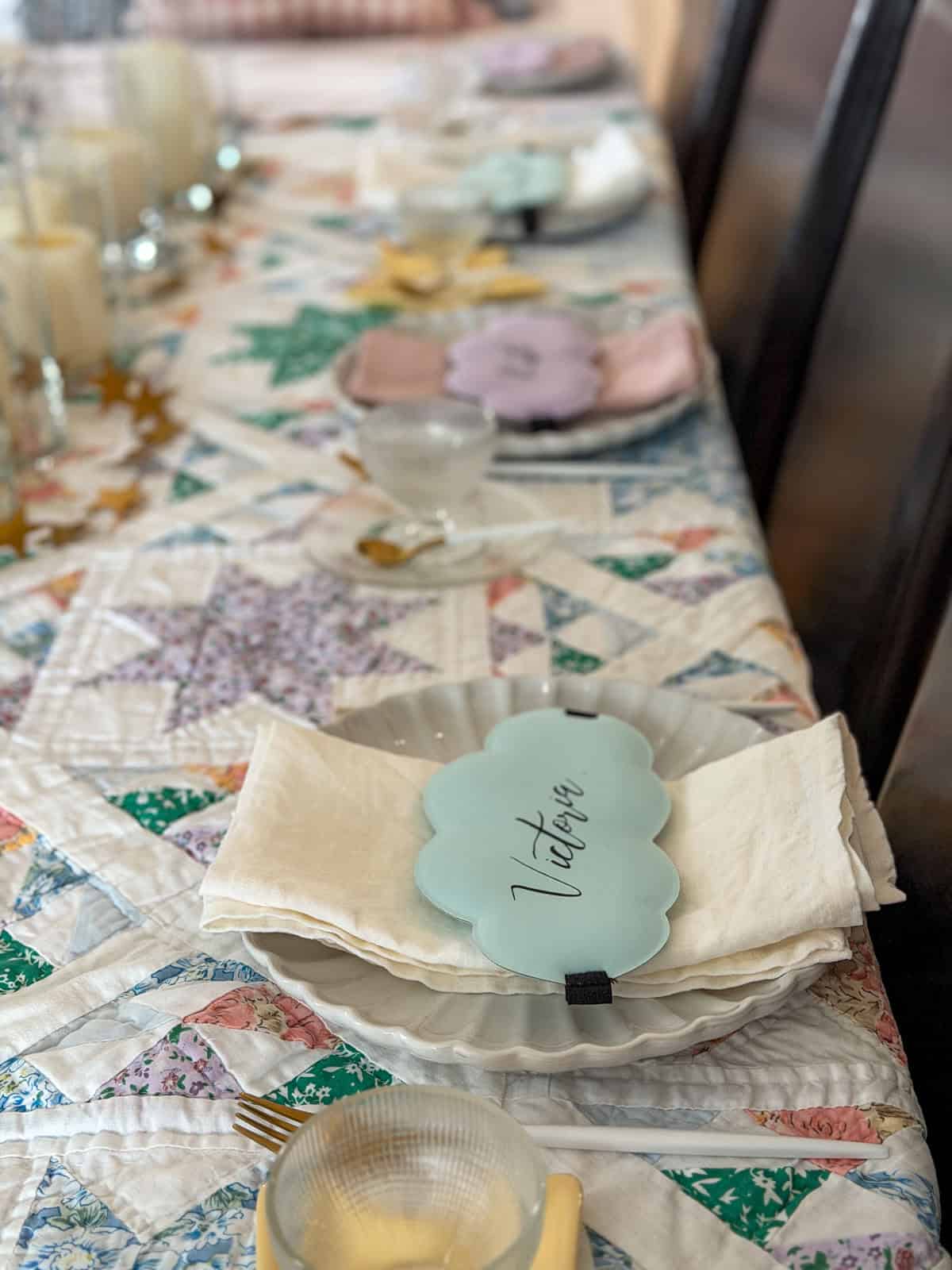 Breakfast for dinner party table set for eight with personalized cloud sleep mask place cards, gold cutlery, star dishes, and vintage star quilt tablecloth.