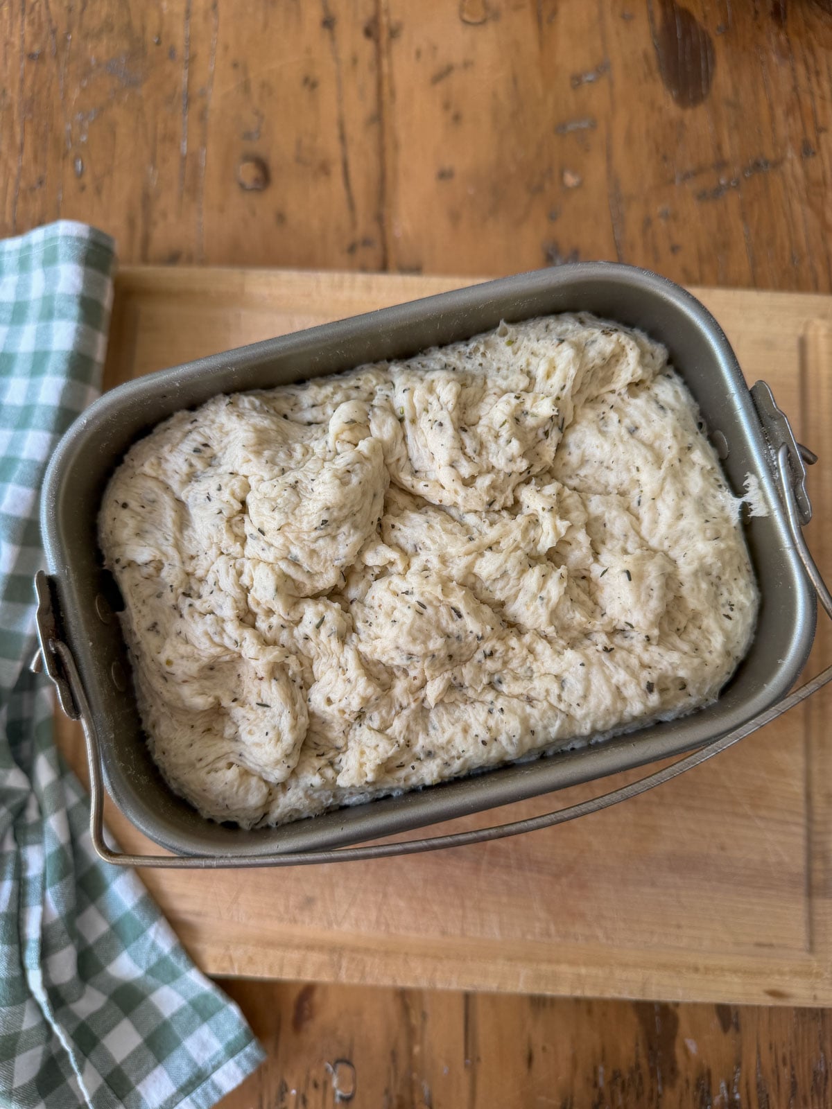 Herb bread dough risen in a bread machine pan after the dough cycle.