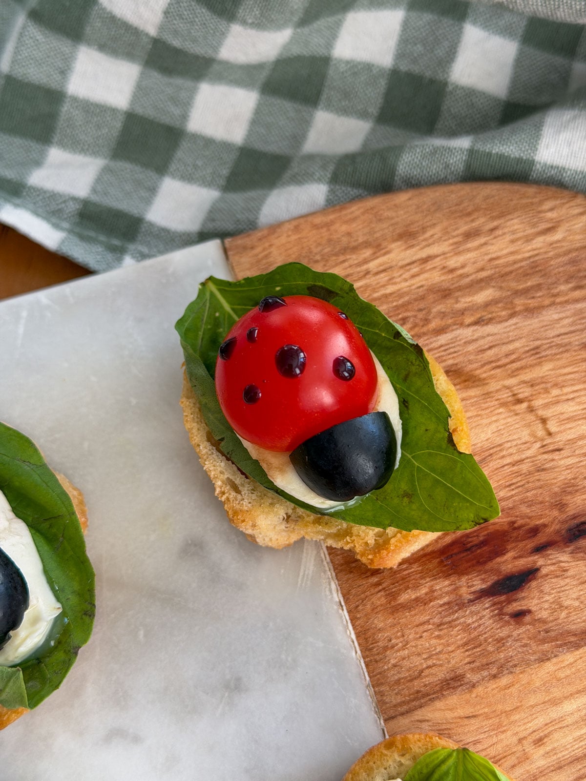 Ladybug caprese bruschetta with balsamic glaze dots forming the ladybug's spots.