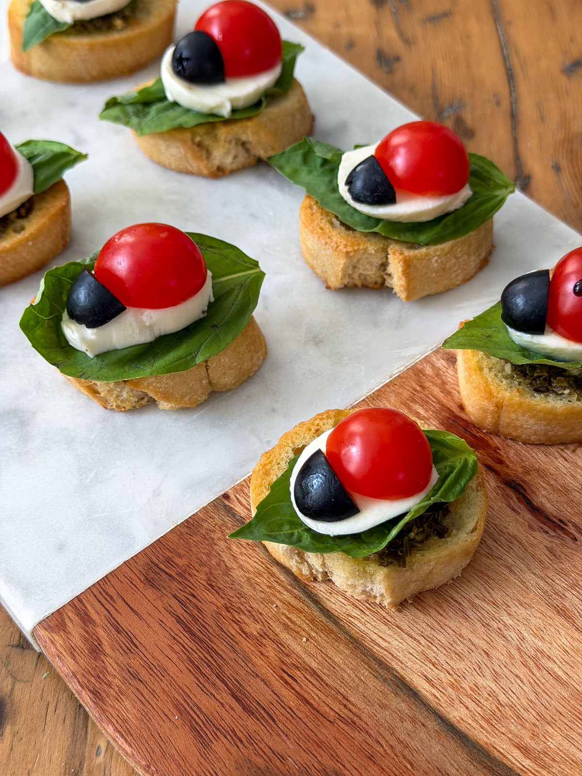 Assembled ladybug caprese bruschetta before adding balsamic glaze spots.
